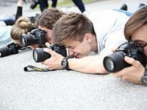 Four photographers lying on the ground to take a photo. Everyone looks through their camera.