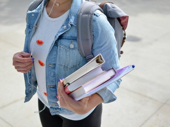 Frau trägt blaue Jeansjacke und hält Buch in der Hand